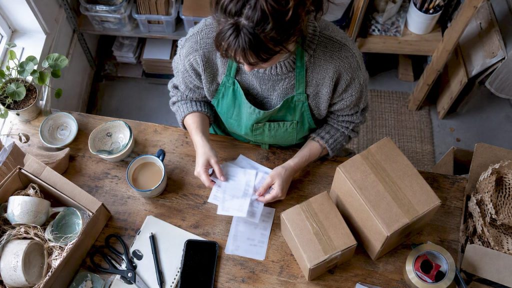 Seller sorting postage receipts beside packed parcels